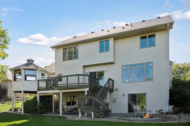 back of property with a wooden deck, an outdoor fire pit, a yard, and a patio area