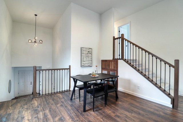 dining area with a towering ceiling, an inviting chandelier, and dark hardwood / wood-style flooring