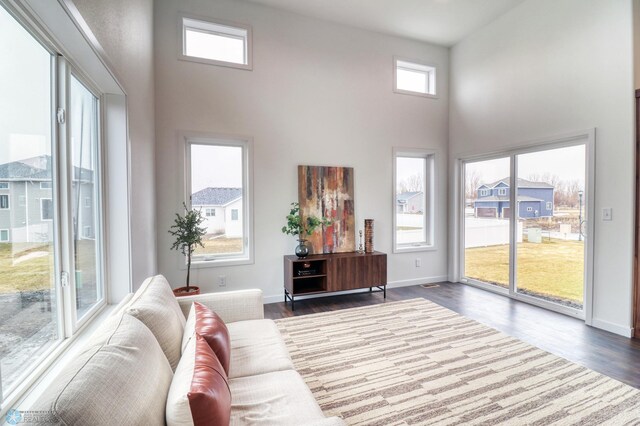 living room featuring a towering ceiling and dark wood-type flooring