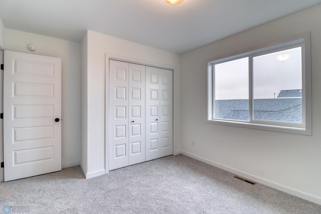 unfurnished bedroom with a closet and light carpet