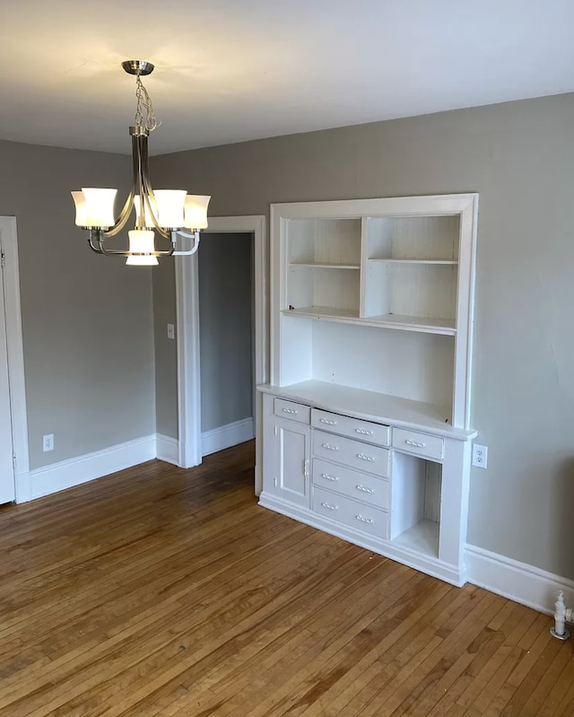 unfurnished dining area with a chandelier and wood-type flooring