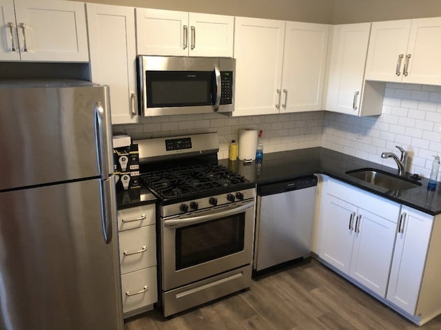 kitchen featuring decorative backsplash, white cabinets, dark hardwood / wood-style flooring, appliances with stainless steel finishes, and sink