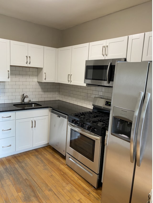 kitchen with white cabinetry, stainless steel appliances, sink, and light wood-type flooring