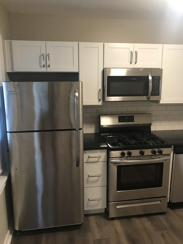 kitchen featuring dark wood-type flooring, backsplash, appliances with stainless steel finishes, and white cabinets