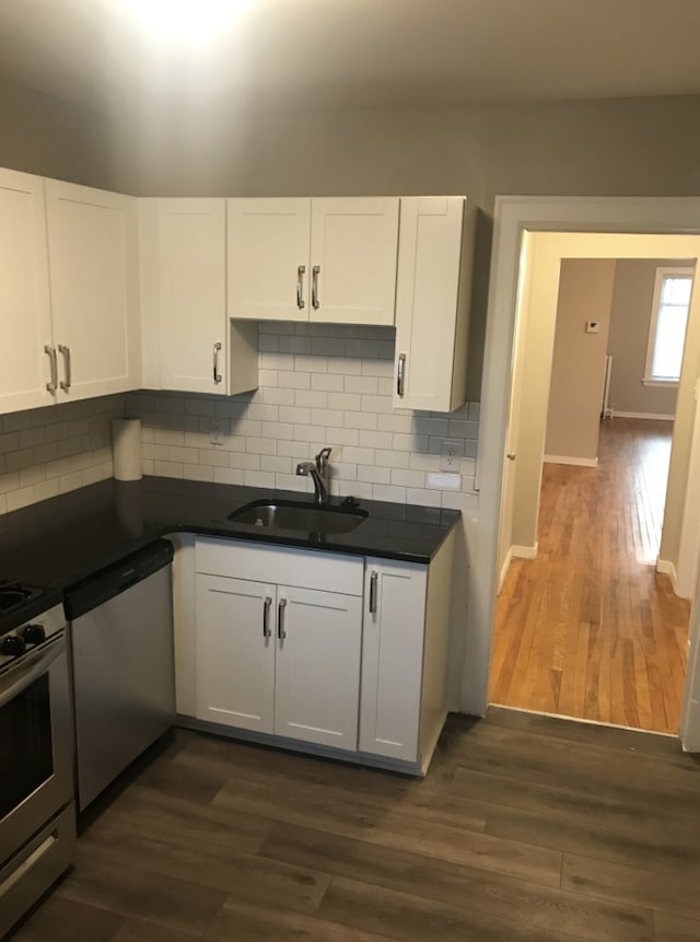 kitchen featuring stainless steel dishwasher, white cabinetry, tasteful backsplash, and dark hardwood / wood-style flooring