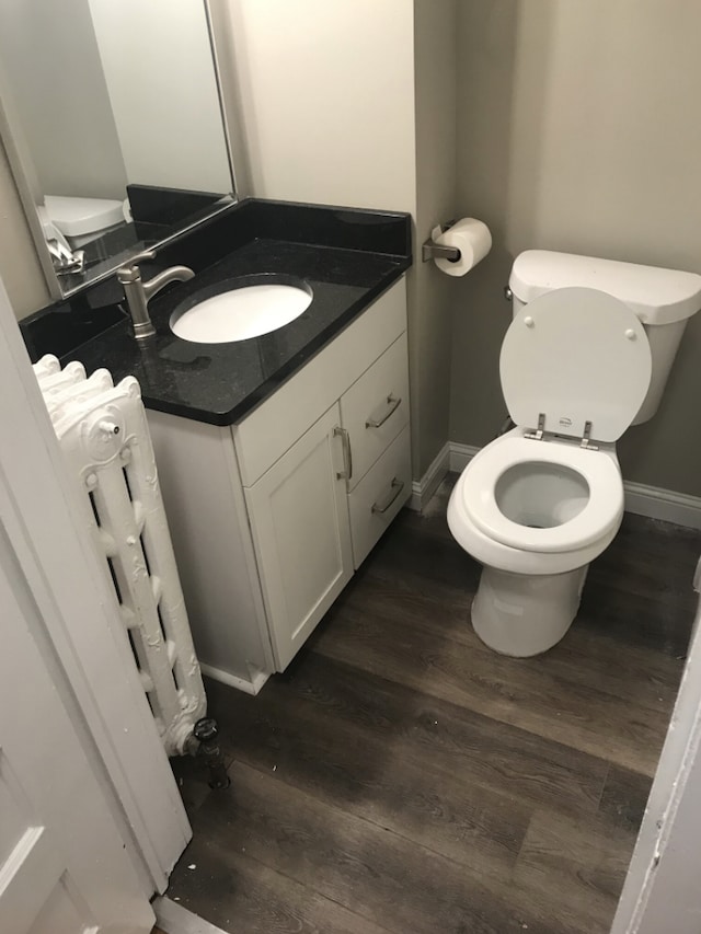 bathroom with vanity, toilet, radiator, and hardwood / wood-style floors