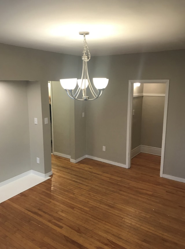 unfurnished dining area featuring dark hardwood / wood-style floors and an inviting chandelier