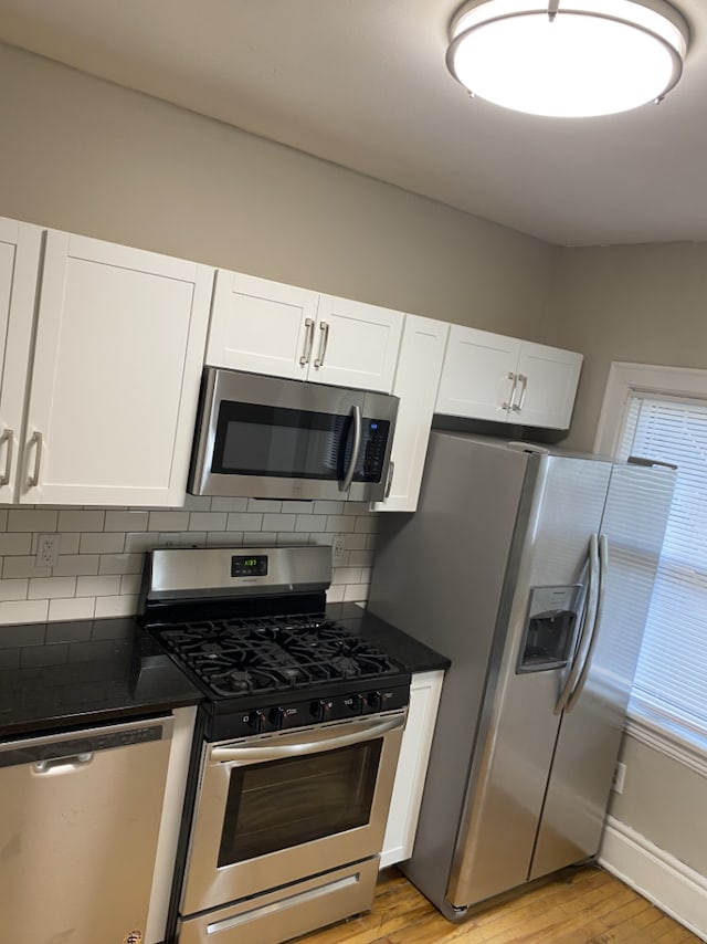 kitchen featuring white cabinetry, light hardwood / wood-style flooring, stainless steel appliances, and backsplash