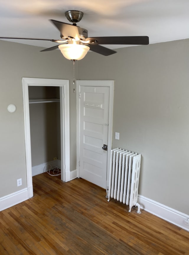 unfurnished bedroom with ceiling fan, dark hardwood / wood-style floors, and radiator