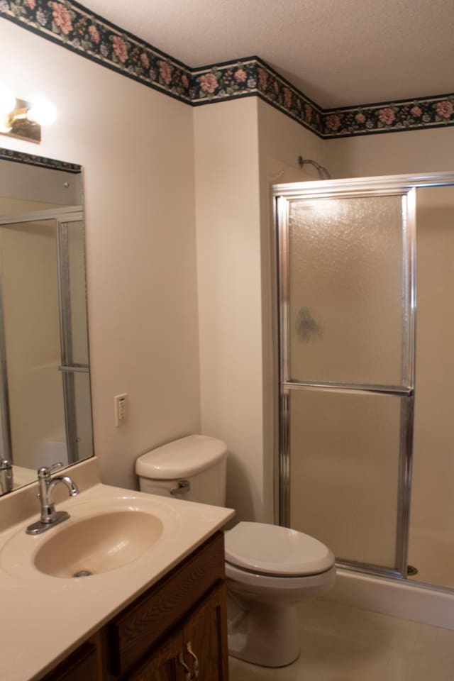 bathroom featuring tile patterned floors, an enclosed shower, a textured ceiling, vanity, and toilet