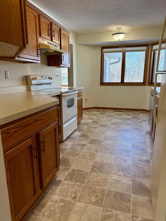 kitchen with electric range, baseboards, brown cabinetry, light countertops, and under cabinet range hood