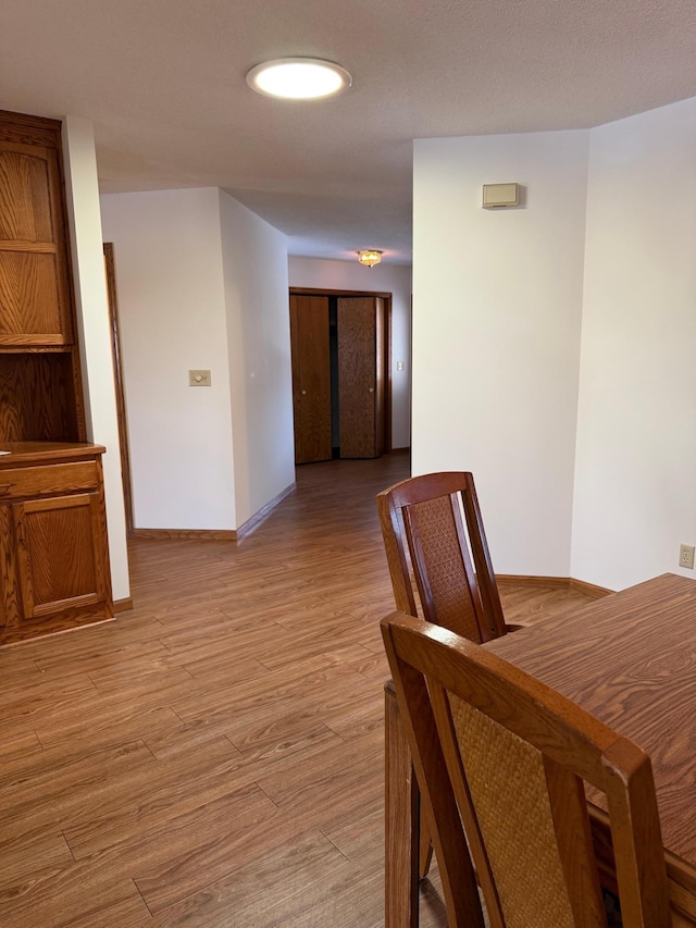 corridor with light wood-style floors and baseboards