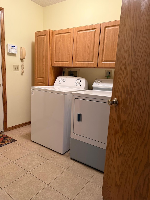 washroom with washer and dryer, cabinet space, baseboards, and light tile patterned floors