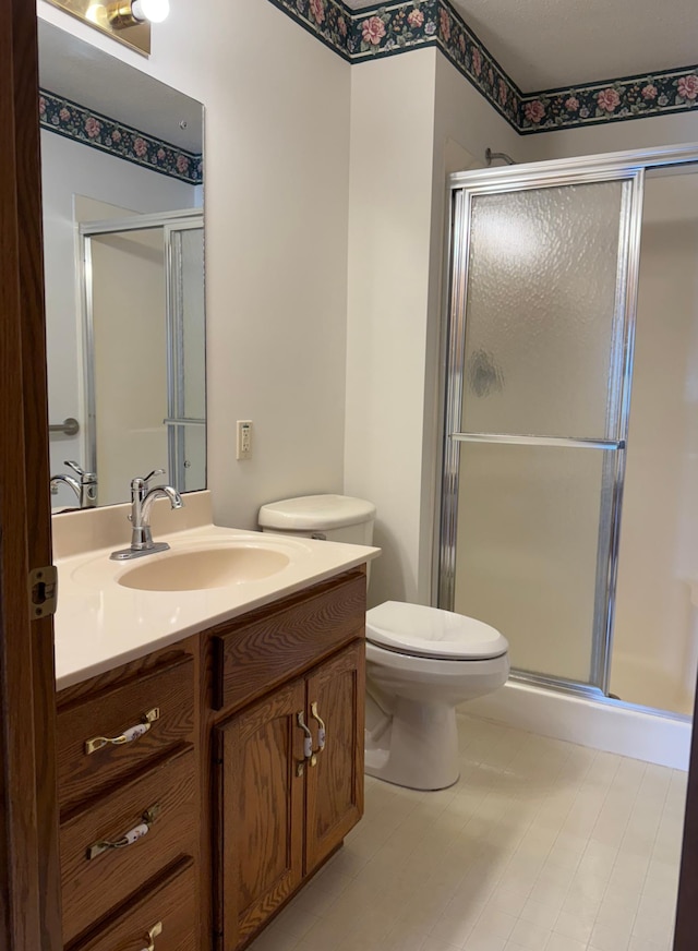 bathroom with toilet, a shower stall, and vanity