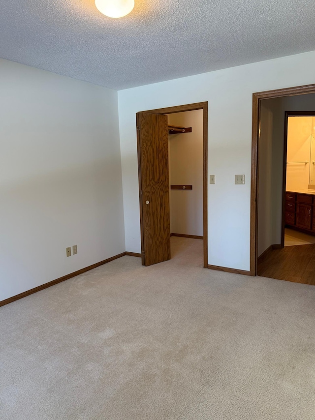 unfurnished bedroom with a closet, carpet flooring, a textured ceiling, and baseboards