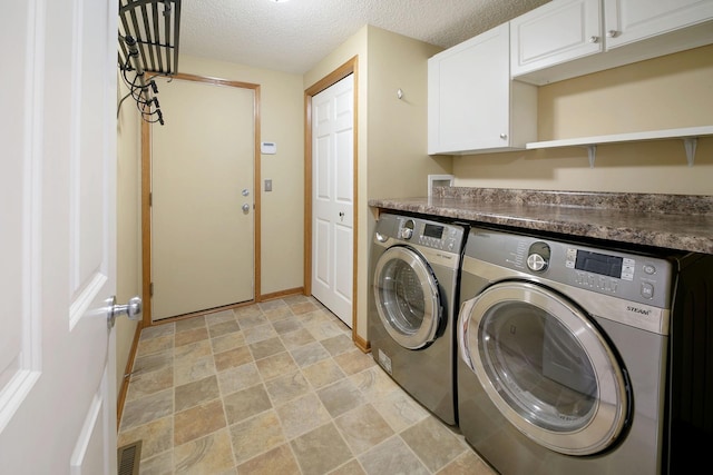 laundry area featuring cabinets, a textured ceiling, and washing machine and clothes dryer