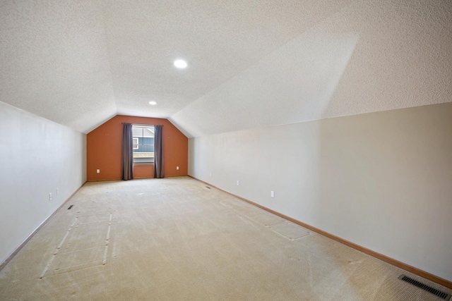 bonus room featuring a textured ceiling, carpet, and lofted ceiling