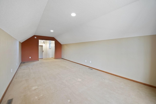 bonus room with a textured ceiling, light colored carpet, and lofted ceiling