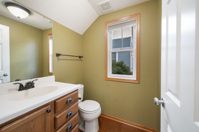 half bathroom featuring a textured ceiling, lofted ceiling, toilet, vanity, and visible vents