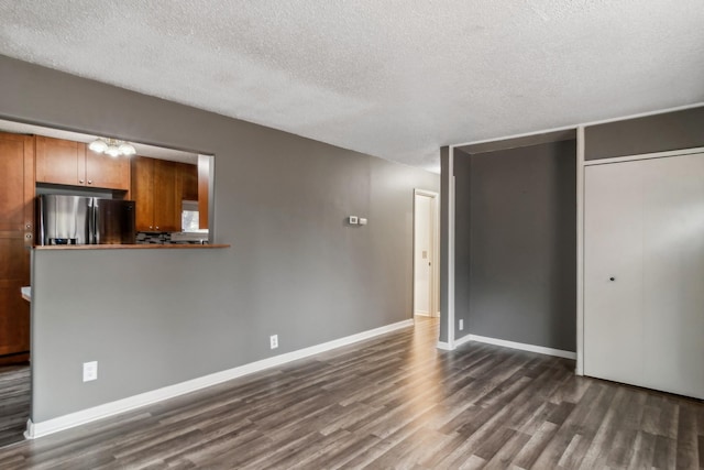 unfurnished bedroom with a closet, a textured ceiling, dark hardwood / wood-style floors, and stainless steel fridge