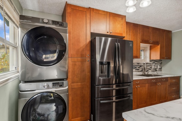 washroom featuring a textured ceiling, stacked washer and dryer, and sink