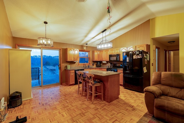 kitchen with light parquet flooring, pendant lighting, black appliances, and a kitchen island