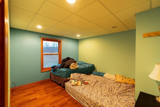 bedroom with a drop ceiling and hardwood / wood-style floors