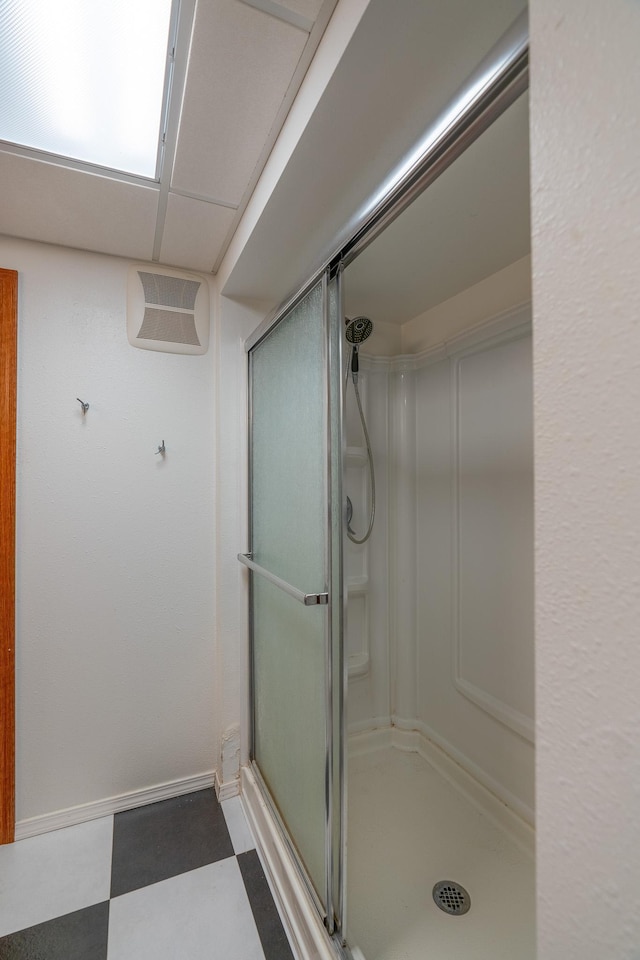 bathroom with a drop ceiling and a shower with shower door