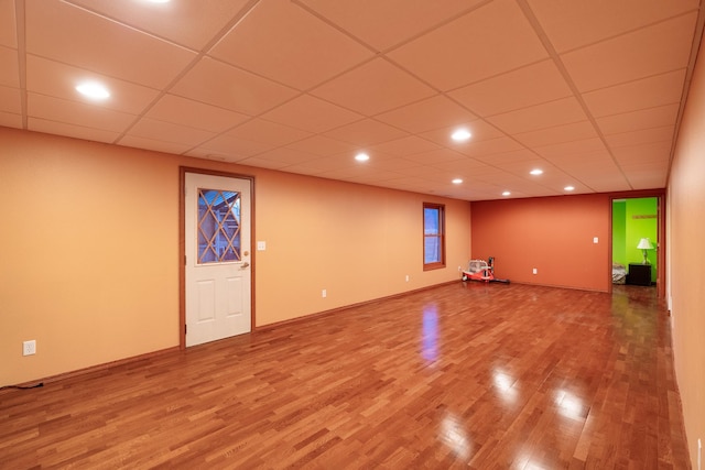 basement featuring a paneled ceiling and hardwood / wood-style flooring