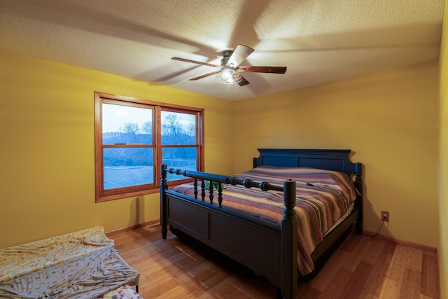 bedroom featuring wood-type flooring, ceiling fan, and a textured ceiling