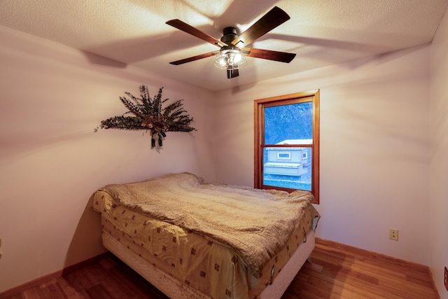 bedroom featuring dark hardwood / wood-style flooring, a textured ceiling, and ceiling fan