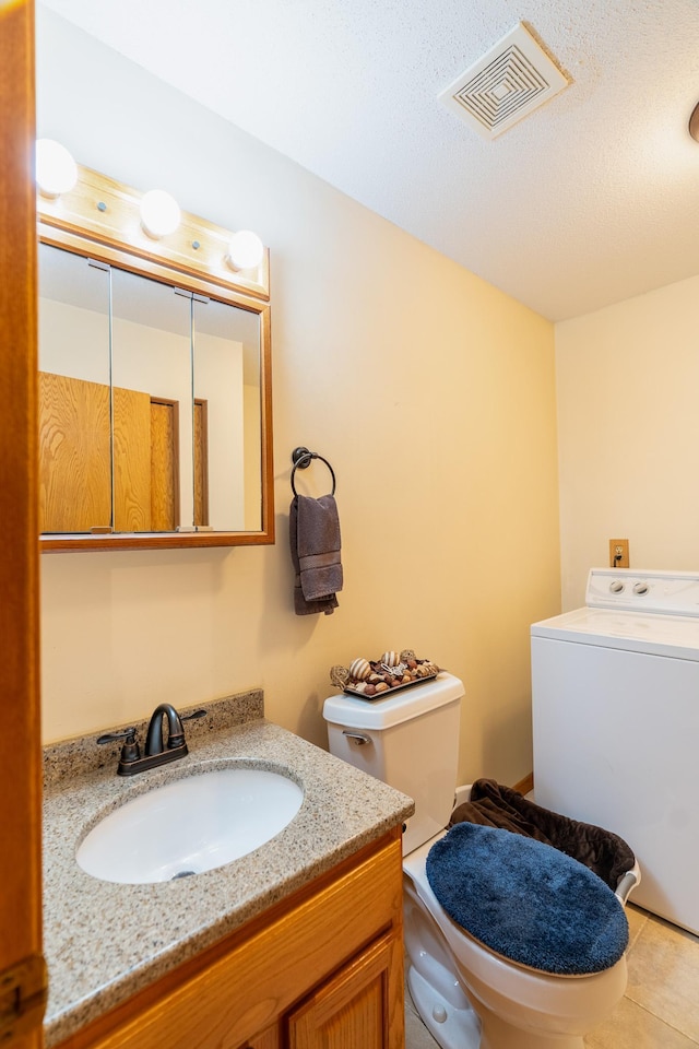 bathroom with tile patterned floors, toilet, a textured ceiling, vanity, and washer / dryer