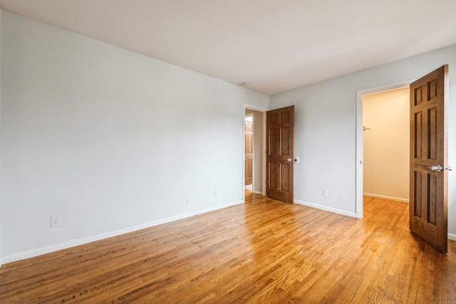 unfurnished bedroom featuring light hardwood / wood-style flooring and a spacious closet