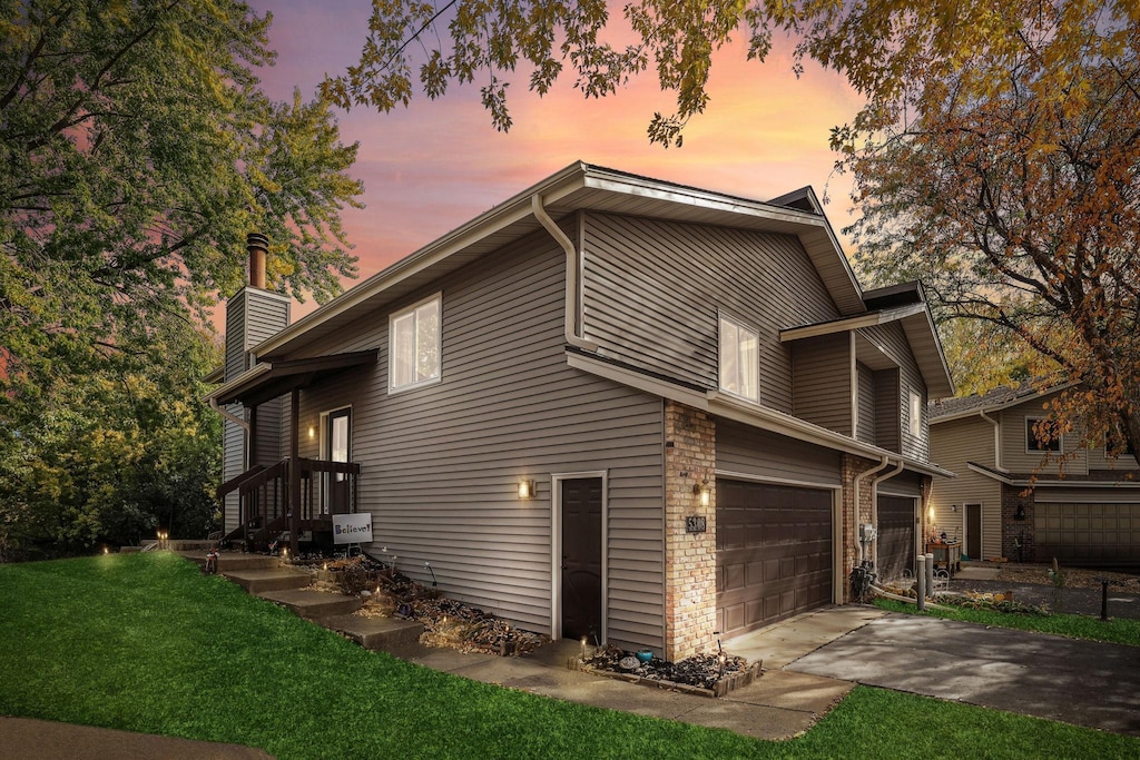 property exterior at dusk featuring a garage and a lawn