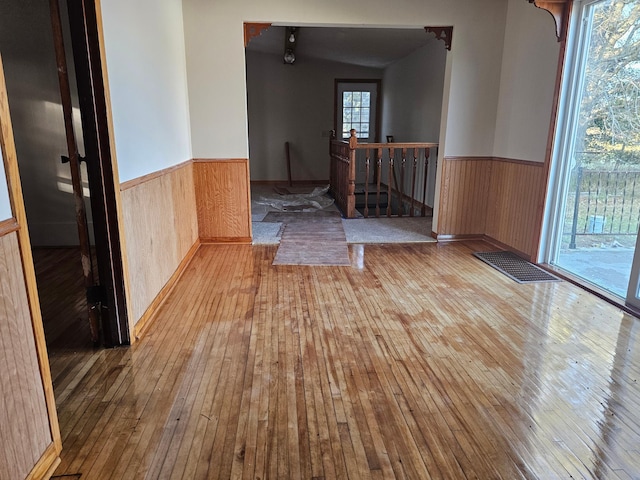 empty room featuring light hardwood / wood-style flooring, lofted ceiling, and wooden walls