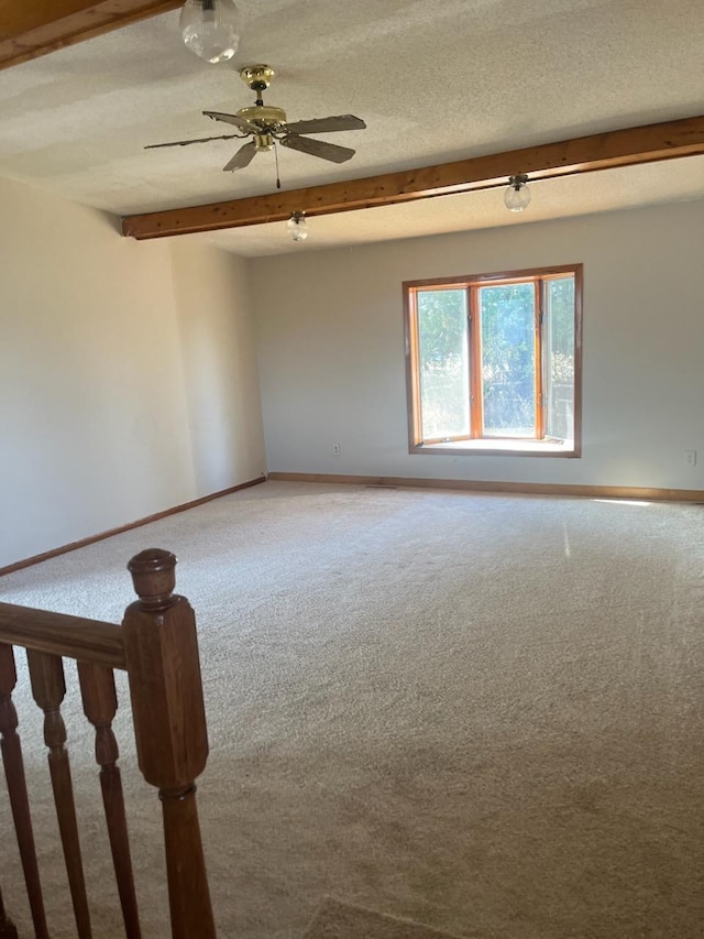 unfurnished room with carpet flooring, a textured ceiling, beamed ceiling, and ceiling fan