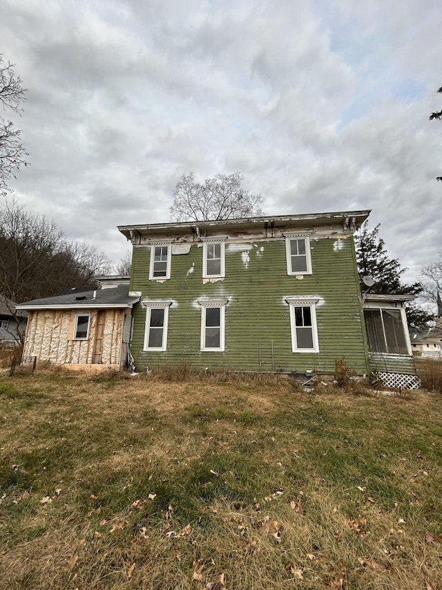 back of property with a sunroom and a yard