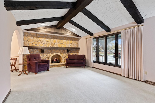 sitting room featuring a fireplace, vaulted ceiling with beams, and carpet floors