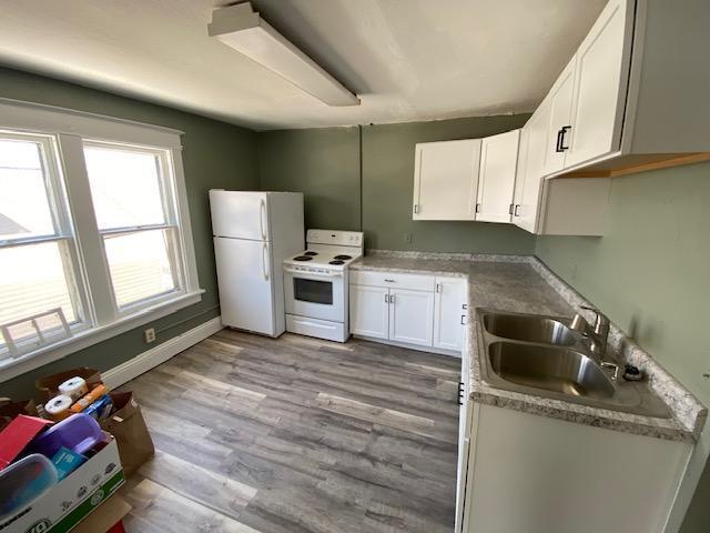 kitchen with white cabinets, sink, light wood-type flooring, and white appliances