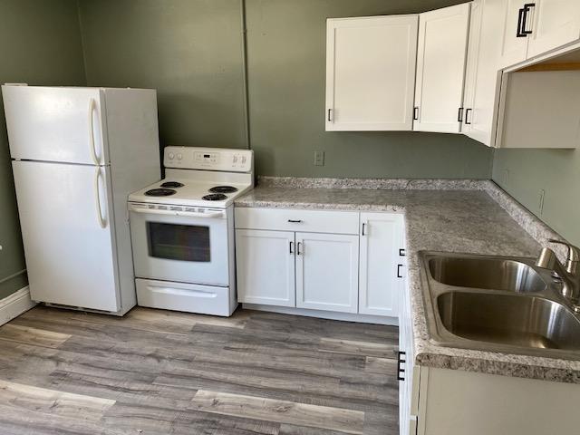 kitchen featuring white cabinets, sink, light wood-type flooring, and white appliances