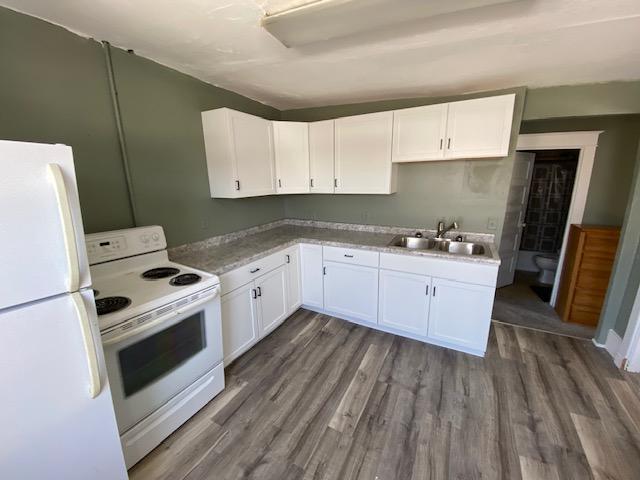 kitchen with dark hardwood / wood-style floors, white cabinets, sink, and white appliances