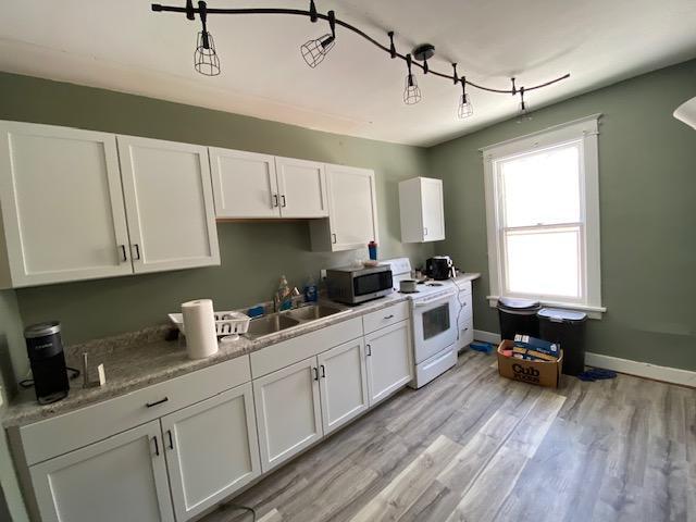 kitchen with light hardwood / wood-style flooring, white cabinets, sink, and white range oven