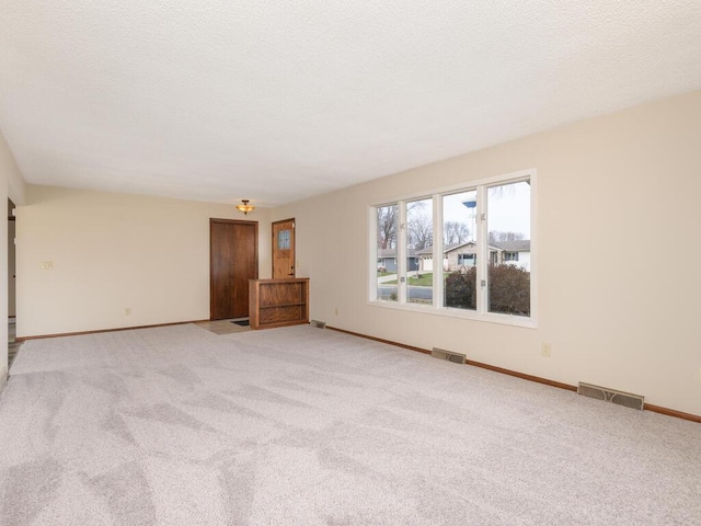 empty room with light colored carpet and a textured ceiling