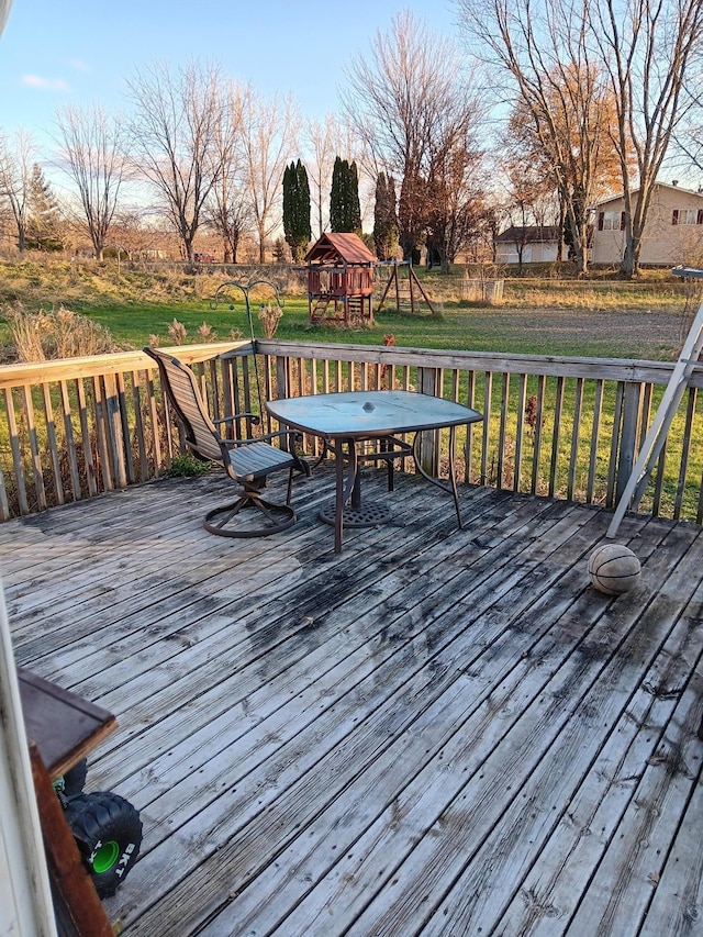 wooden terrace with a playground and a lawn