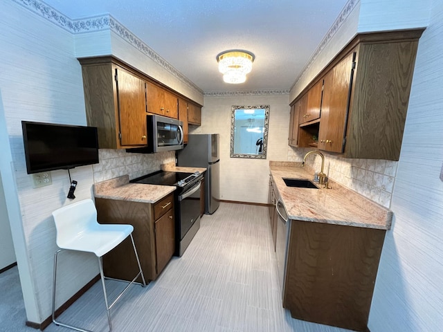 kitchen featuring appliances with stainless steel finishes, light stone countertops, sink, and decorative backsplash