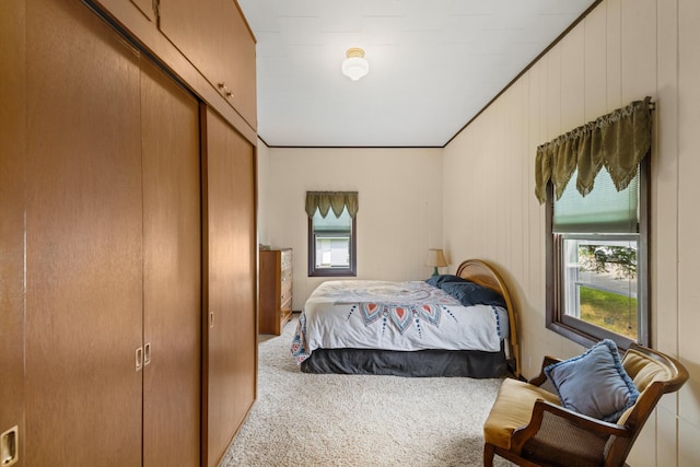 carpeted bedroom featuring a closet, wood walls, and ornamental molding