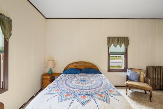 carpeted bedroom featuring radiator heating unit and wooden walls