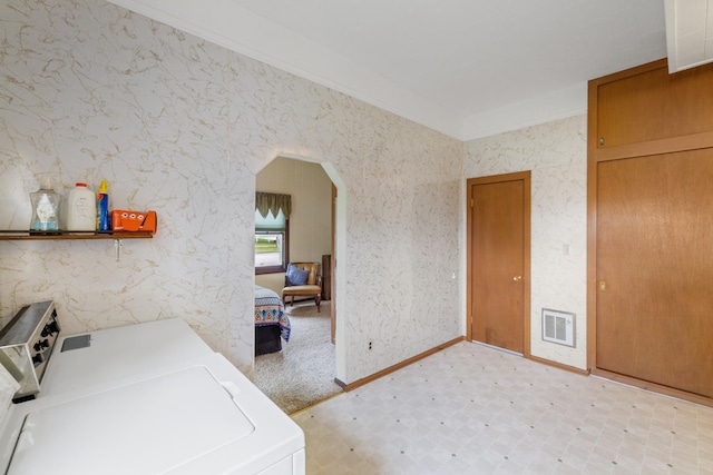 clothes washing area with ornamental molding, light carpet, and washer and dryer