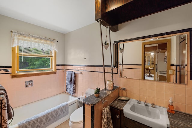 bathroom with tile walls, vanity, a tub, and toilet