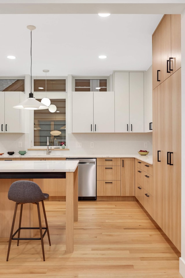 kitchen featuring dishwasher, light brown cabinets, hanging light fixtures, light wood-type flooring, and white cabinetry